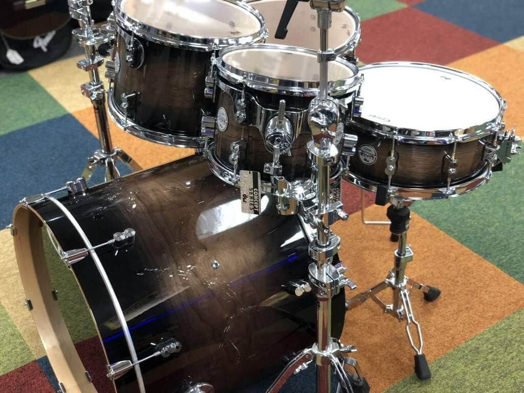 PDP Concept Exotic 5-Piece Shell Pack in Walnut and Charcoal Burst finish, showcasing the drum set's elegant design and craftsmanship.