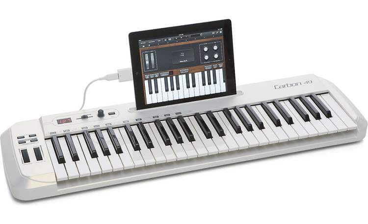 Samson Carbon 49 USB MIDI keyboard controller with 49 keys, assignable controls, and an iPad stand, featuring Komplete Elements software.