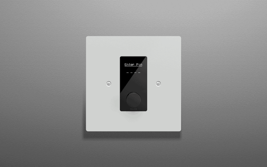 Xilica Designer IP-Based Wall Control featuring a recessed rotary encoder and configurable OLED display, designed with a white coated aluminium faceplate for EU/UK wall-box installations.